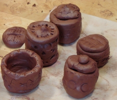 Zdjęcie kilku małych glinianych naczyń samodzielnie wykonanych przez dzieci uczestniczące w zajęciach. 