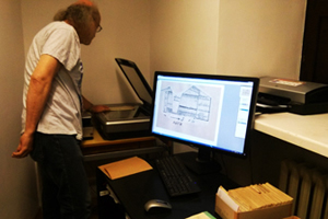 Zdjęcie, na którym widać osobę pracującą przy digitalizacji archiwaliów - rysunków