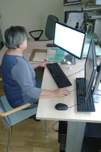 Zdjęcie, na którym widać osobę pracującą przy opisywaniu archiwaliów - rękopisów prac naukowych i notatek wielkich archeologów.